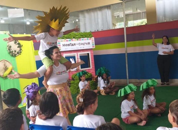 Crianças e educadoras participando da apresentação teatral do projeto Hortar e Colher